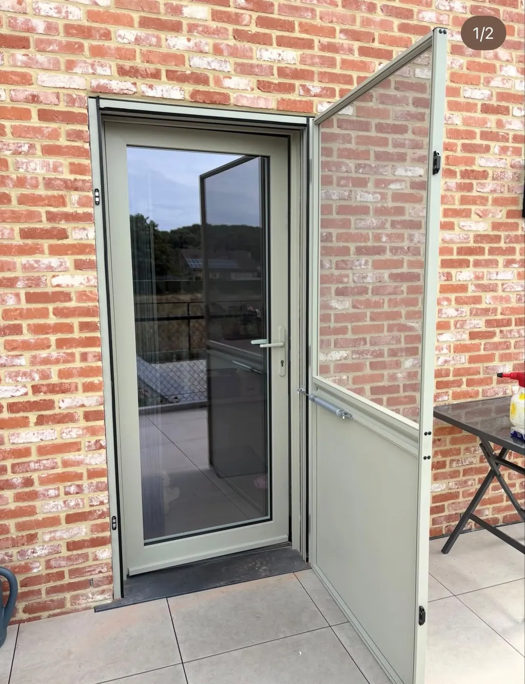 Groene deur met glaspartij, geopend naar het terras