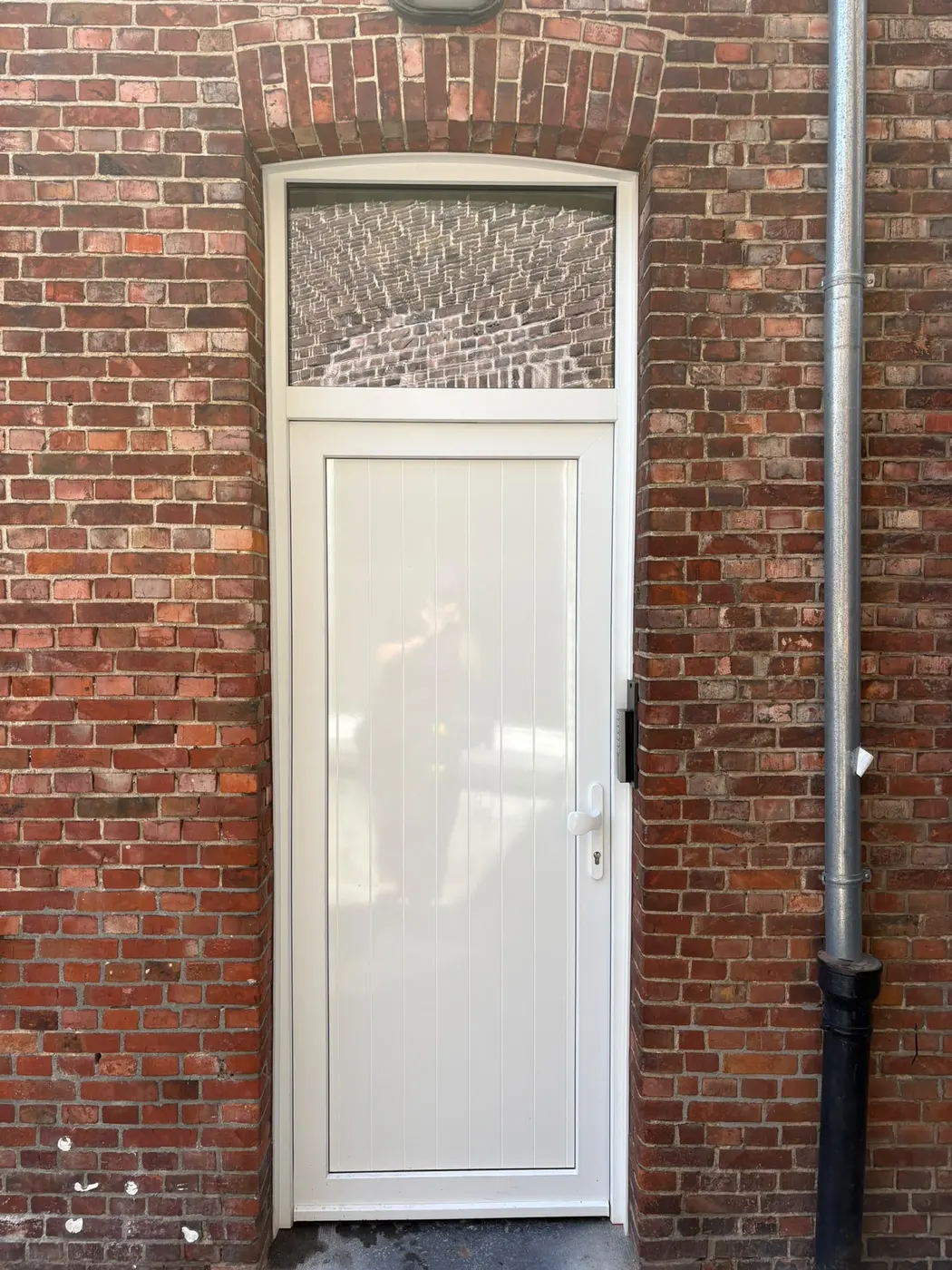 Witte deur met bovenlicht in een oudere bakstenen woning