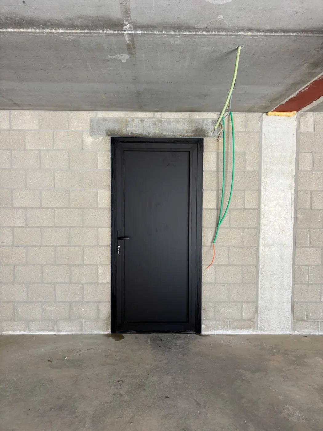 Zwarte deur tussen garage en woning tijdens renovatie